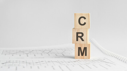 three stone cubes on the background of white financial statements, tables with the word CRM. Strong business concept