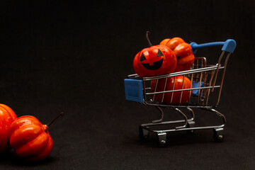 Orange pumpkins in a cart and scattered pumpkins on a black background. flat lei on the topic of...