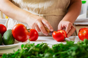 Chef slicing tomato using knife on the table in restaurant. Process of cutting and preparation food in kitchen.