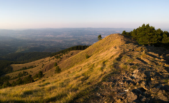 View from the top of Gostilj on the mountain Ozren on the slopes and villages in the valley, a landscape of hilly Balkans with haze on the horizon at evening