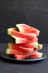 slices of watermelon.ripe red watermelon on the black background. fresh watermelon on the grey plate on the table with copy space. vertical