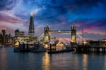The lifted Tower Bridge and illuminated skyline of London, United Kingdom, during dusk just after sunset