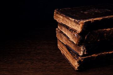 Stack of old worn shabby Jewish books in leather binding in the dark. Closeup. Selective focus....