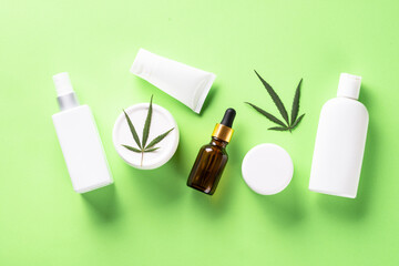Cannabis cosmetic products. Cream, soap, serum bottle and others. Flat lay image on green background.