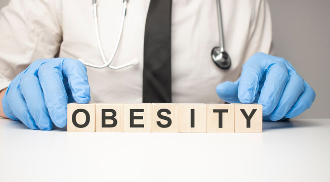 Doctor holds wooden cubes in his hands with text OBESITY