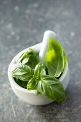 Fresh green basil leaves in mortar.