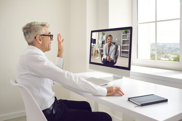 Man sitting in front of office computer and having virtual work meeting with business colleague....