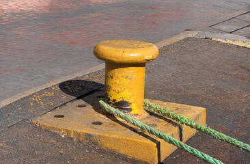 yellow bollard and tied rope on pier