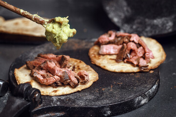 Process of cooking tacos with grilled flank beef steak with handmade guacamole