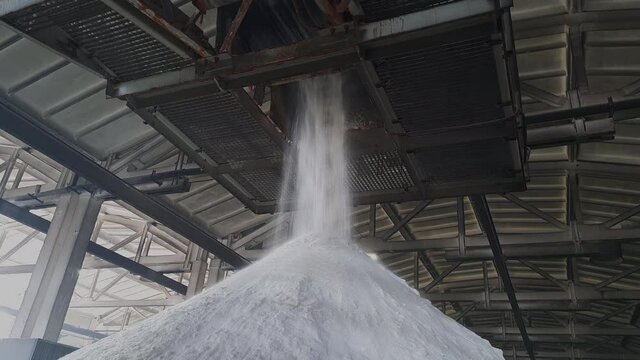Ammonium sulfate powder pour in a pile inside a warehouse of chemical plant. Mineral organic fertilizers for agriculture industry.