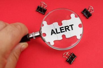 A man looks through a magnifying glass at puzzles with the inscription - ALERT