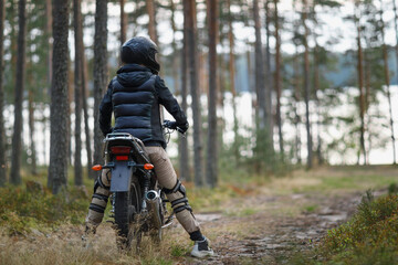 a woman on a motorcycle in nature. motorcyclist walk through the forest