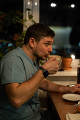 a man drinks coffee from a glass mug at night