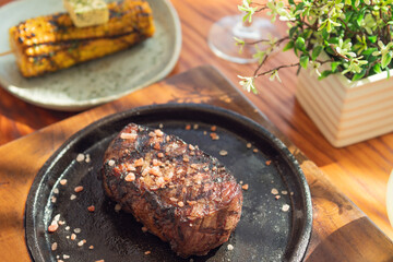 Grilled steak and garnish yellow corn on wooden table. Gourmet food.