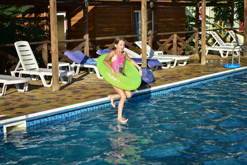 girl with a circle jumping from the side to the pool