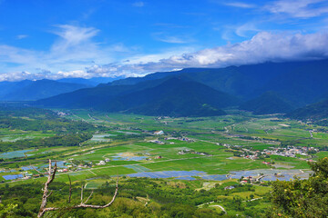 beautiful landscape of mountains with paddy field and farmhouses under blue sky in sunny summer 
