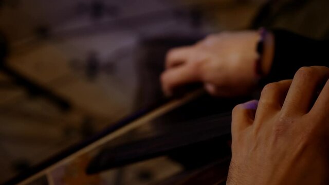 Artist plays with a bow on the strings of the cello in the darkness. Close-up musician plays with a bow of a violoncello