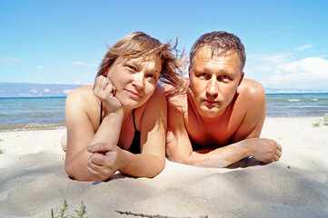 Fototapeta premium A couple sunbathes on the white sand of Lake Baikal
