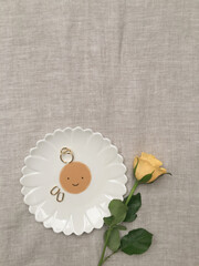 A plate with a picture of the sun, ornaments and a yellow rose.