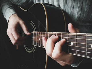 man's hands playing acoustic guitar closeup