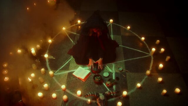 Witch woman sitting in pentagram circle and reading spell. Evil sorceress making rite and sacrifices at night, using black witchcraft, cow skull and candles on floor, shouting. Halloween time.