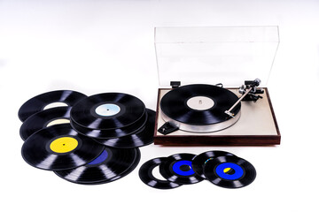 Record player next to vinyl records on white background photographed i