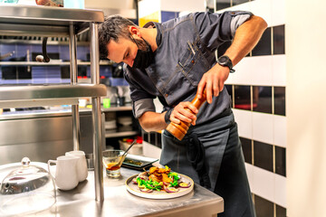 kitchen chef spicing up a dish from his menu