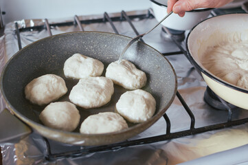 Yeast pancakes are fried in oil in frying pan on stove