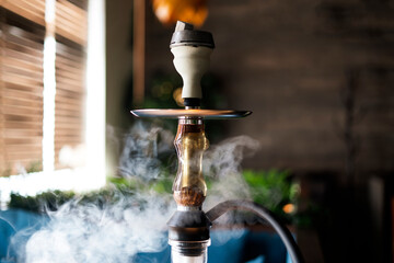 a glass hookah shisha with bowl standing on the table in lounge zone