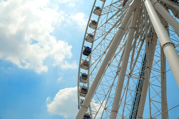 Fototapeta na wymiar Giant Ferris wheel with numbered cabins in the park - Bright blu