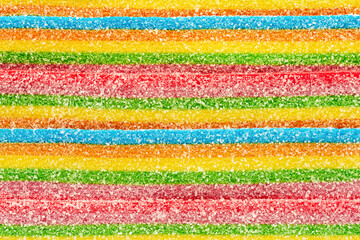Background of rainbow sour jelly candies strips in sugar sprinkle. Top view