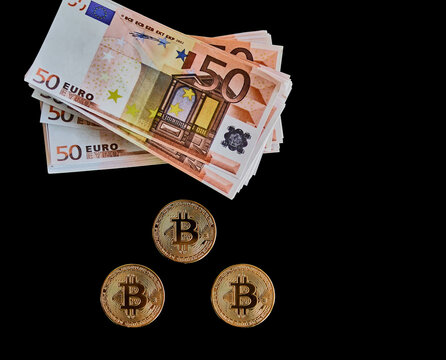 Three Bitcoin coins next to several 50 euro banknotes on a black background. Concept of economics, power, money, exchange, anonymity.