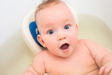 Surprised little baby swimming in the bath. American child bathroom surprised for game design. Pure water. Curly hair. Funny kid. Open mouth - 457411085