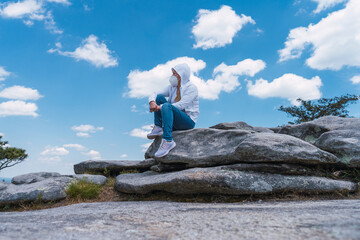 Obraz premium Woman sitting in the top of the mountain wearing a face mask looking around