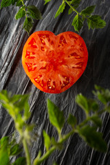 Heart shape tomato on dark background. Solanum lycopersicum.