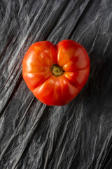 Heart shape tomato on dark background. Solanum lycopersicum.