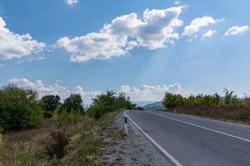 Asphalt empty road on a mountain on an autumn day and white clouds in the sky. Beautiful natural panoramic background concept