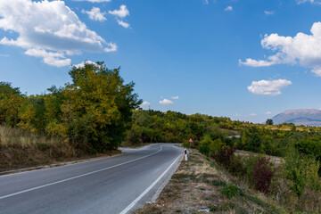 Fototapeta na wymiar An asphalt empty road on a dry mountain ( Suva Planina ) in Serbia on an autumn day and white clouds in the sky. Beautiful natural background concept