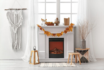 Comfortable fireplace with beautiful autumn leaves in interior of room