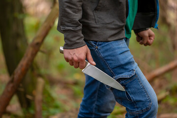 
A man with a large knife in the forest, close-up, selective focus. Concept: attack on passers-by,...