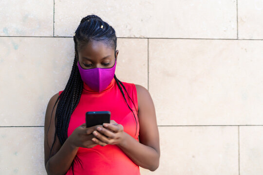 woman with African braids sending a message from her smartphone