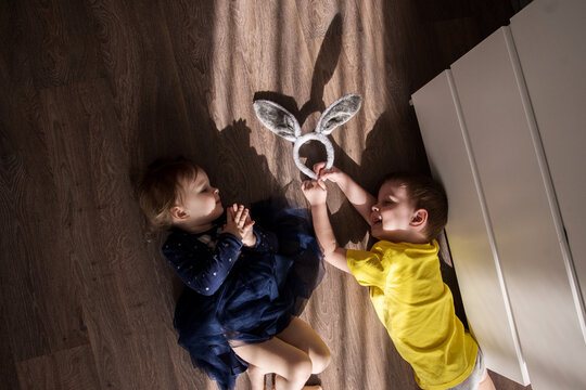 brother and sister play on the floor. children are bored at home