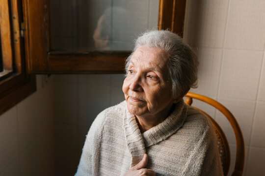 portrait of elderly woman sitting looking out the window