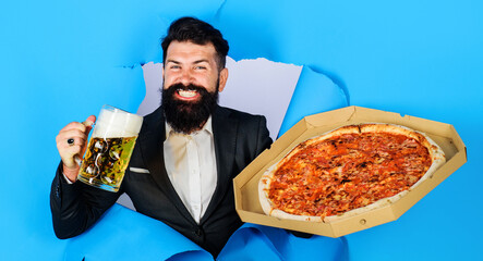 Bearded man with tasty pizza and beer looking through paper hole. Enjoy delicious pizza and cold beer.