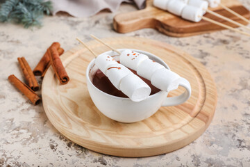 Naklejka premium Snowmen made of soft marshmallows and cup of hot chocolate on grunge background