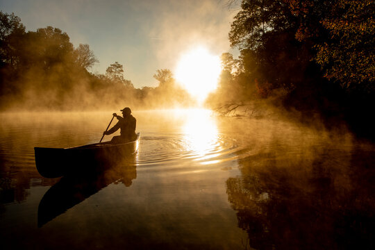 Sunrise canoe ride on foggy river.