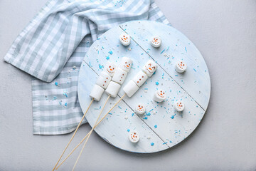 Board with snowmen made of soft marshmallows on grey background