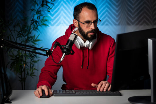 Content creator with headphones and microphone streaming a program online on the internet. Podcast presenter broadcasting on-air program. Content recording for internet program.