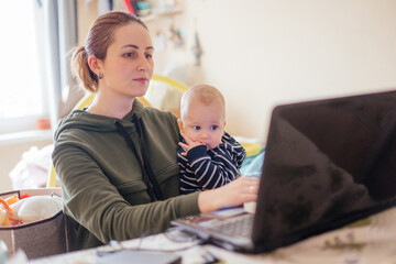 Young mother working from home together with her baby