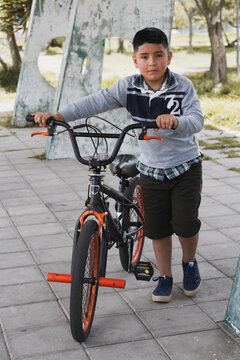Boy walking with his bicycle.